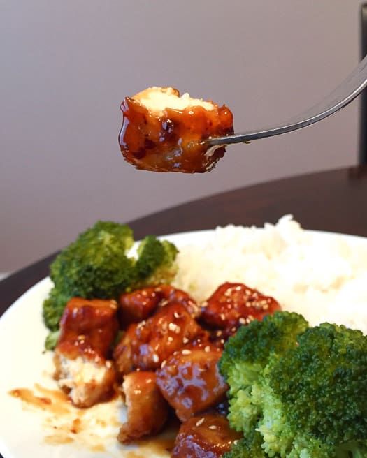 vegan general tso tofu with broccoli and rice on a plate.