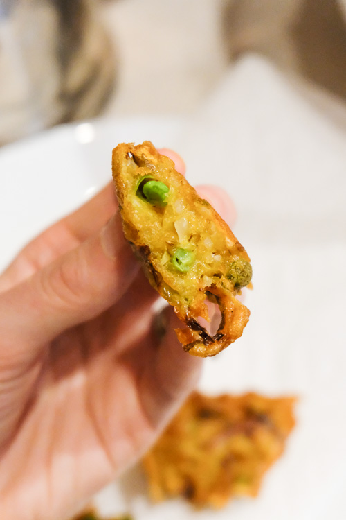 A fried pakora cut in half, showing that the outside is crisp while the inside is soft but cooked.