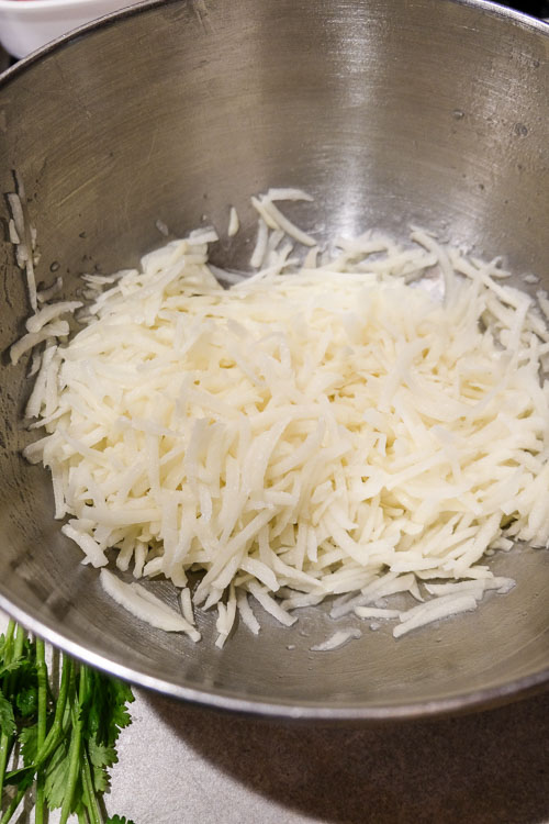 Grated potatoes in a bowl, after draining.