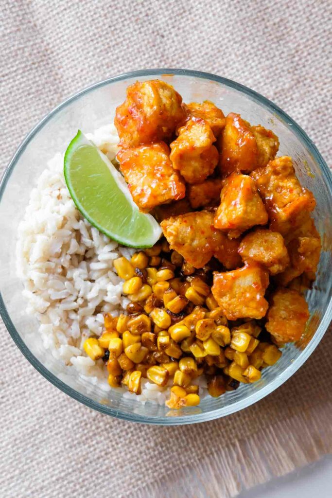 top-down view of tofu, rice, corn, and a lime.