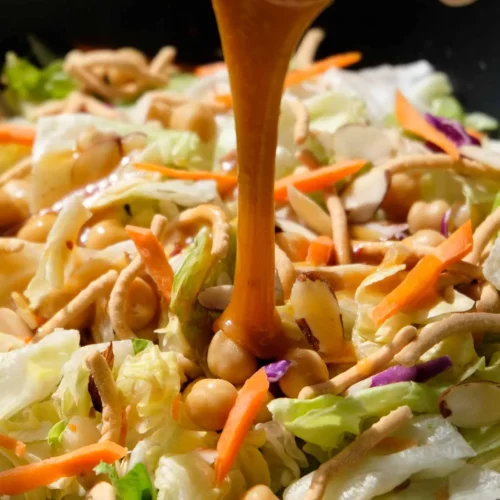 Dressing being poured over an Applebee's copycat asian salad