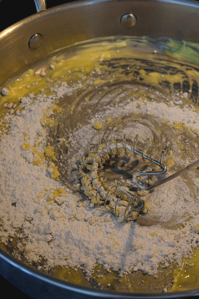 Flour being mixed into melted vegan butter in a pan.