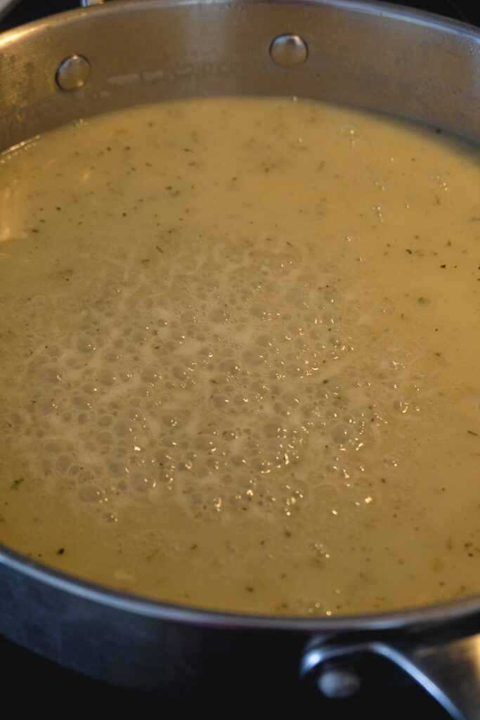 A gravy mixture coming to a boil in a skillet.