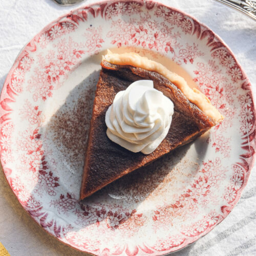 Top-down view of a pumpkin pie on a plate with whipped cream topping.
