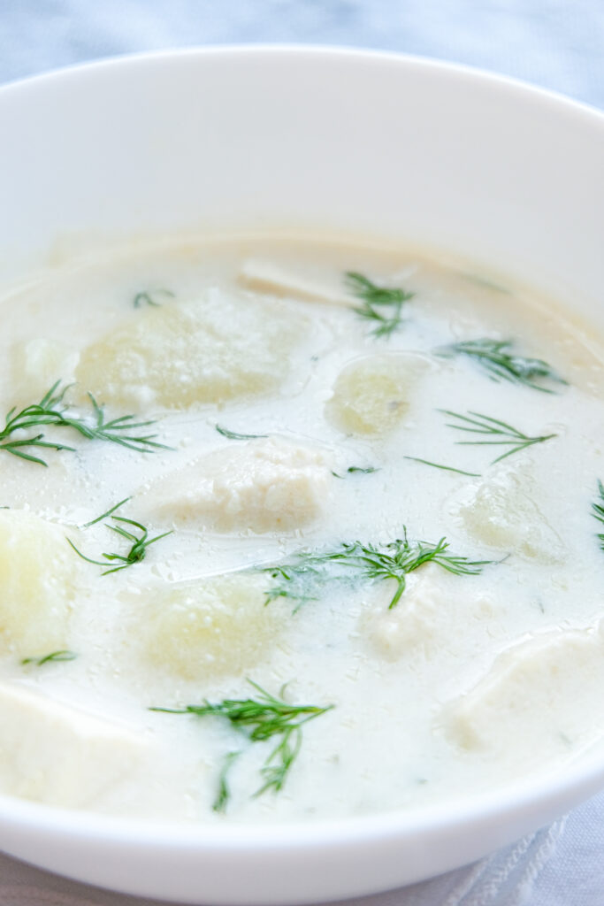 Close up photo of a bowl of creamy potato soup with dill and tofu.